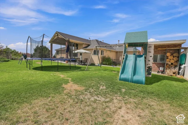 Expansive backyard with a covered patio, brick exterior, and a detached storage area