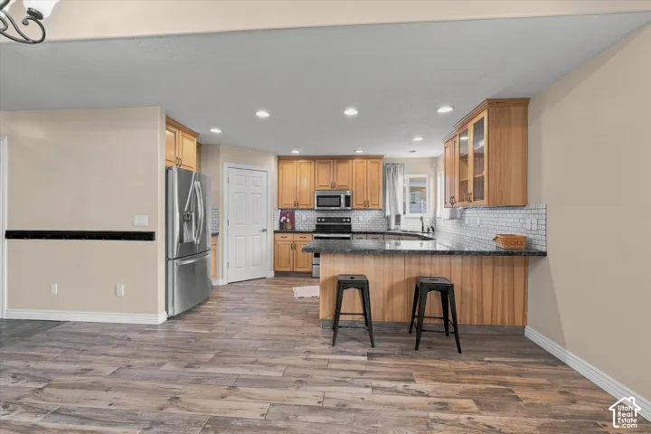 Spacious kitchen featuring wood-finish cabinetry, stainless steel appliances, dark countertops, and a white subway tile backsplash