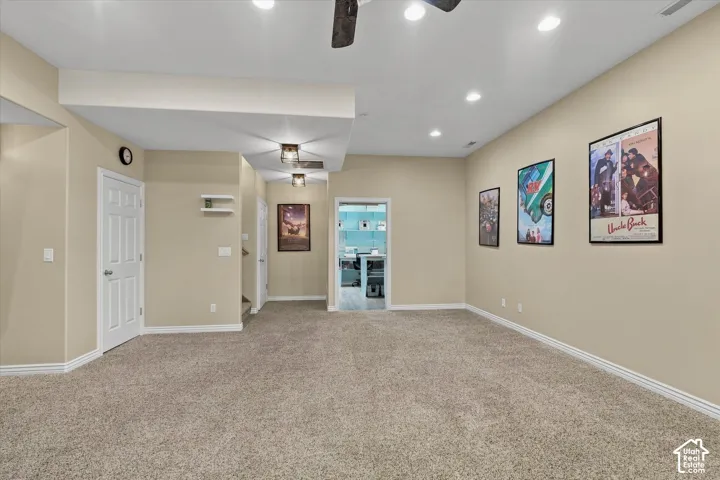 Carpeted floor, recessed ceiling lights, flush mount ceiling lights, white trim, and a white paneled door