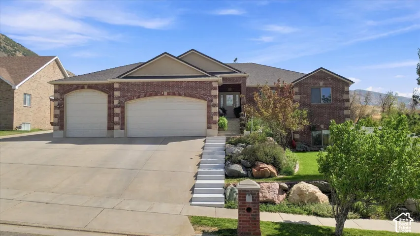 Brick exterior with stone accents, attached two-car garage, terraced landscaping, and a concrete driveway
