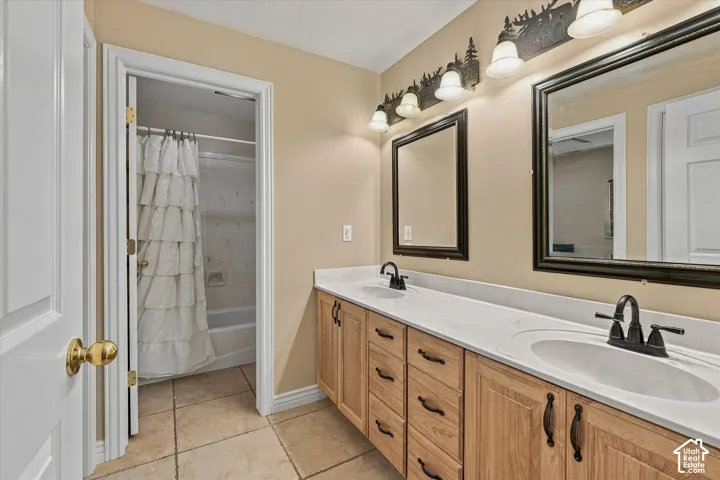 Double vanity with white countertop, dual black-finish faucets, two framed mirrors, and wood-finish cabinetry
