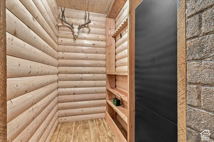 Log-style wood paneling, wood-finish flooring, built-in shelving, and a dark-paneled cabinet