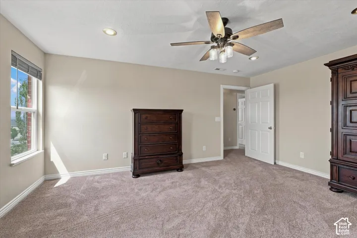 Carpeted room featuring a ceiling fan with integrated lighting, recessed lighting, and a white paneled door
