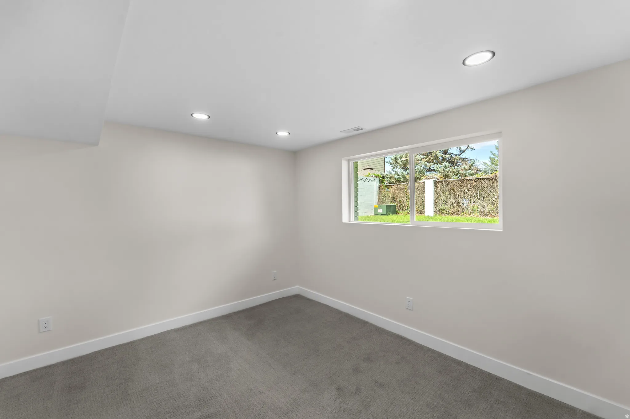 Recessed lighting, light gray carpet, and a large window