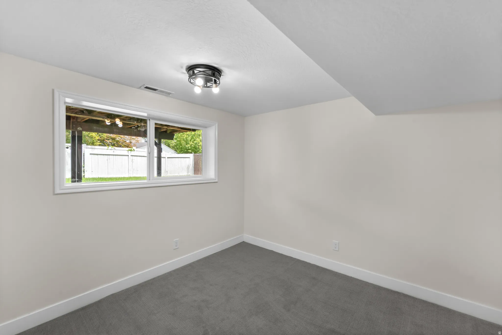 Wall-to-wall carpeting and a flush-mount ceiling light fixture with three exposed bulbs