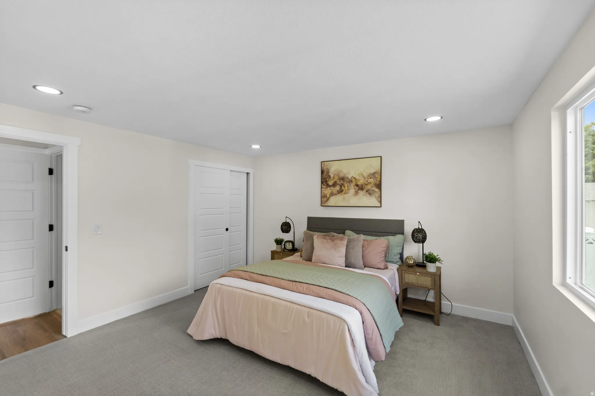Recessed ceiling lighting, white trim, sliding closet doors, and a window with white casing