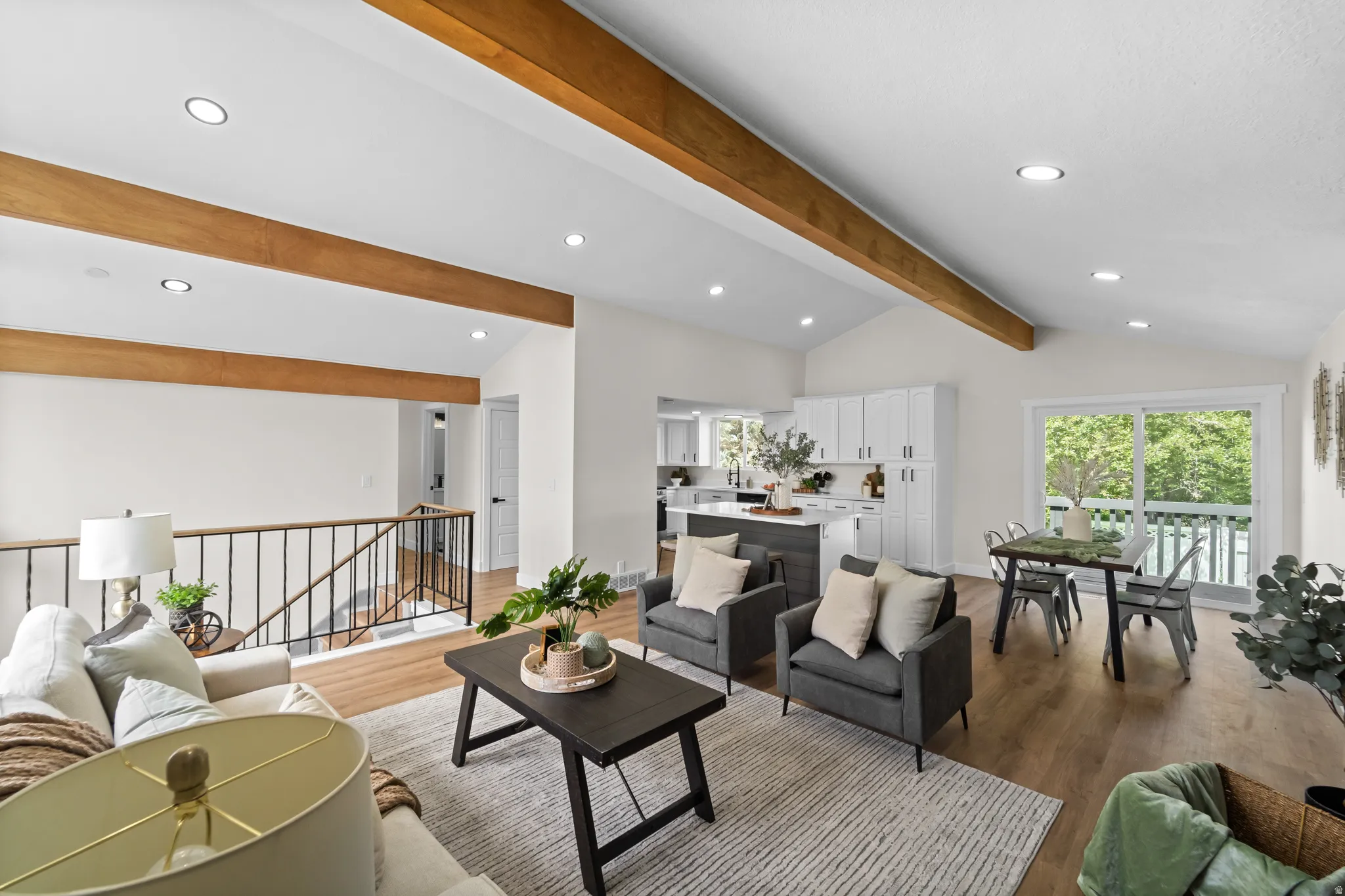 Vaulted ceiling with exposed wood beams, wood-finish flooring, recessed lighting, and a sliding glass door to an exterior deck