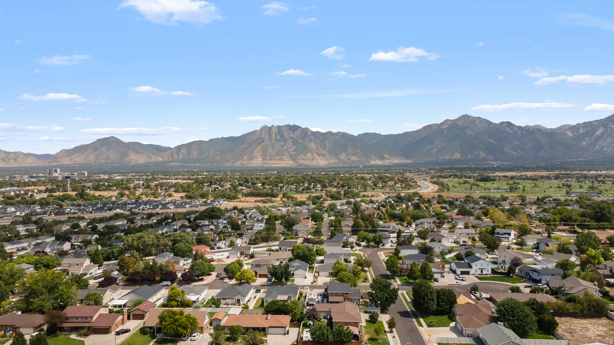Expansive aerial perspective showcasing a residential neighborhood with surrounding mountains and a clear sky