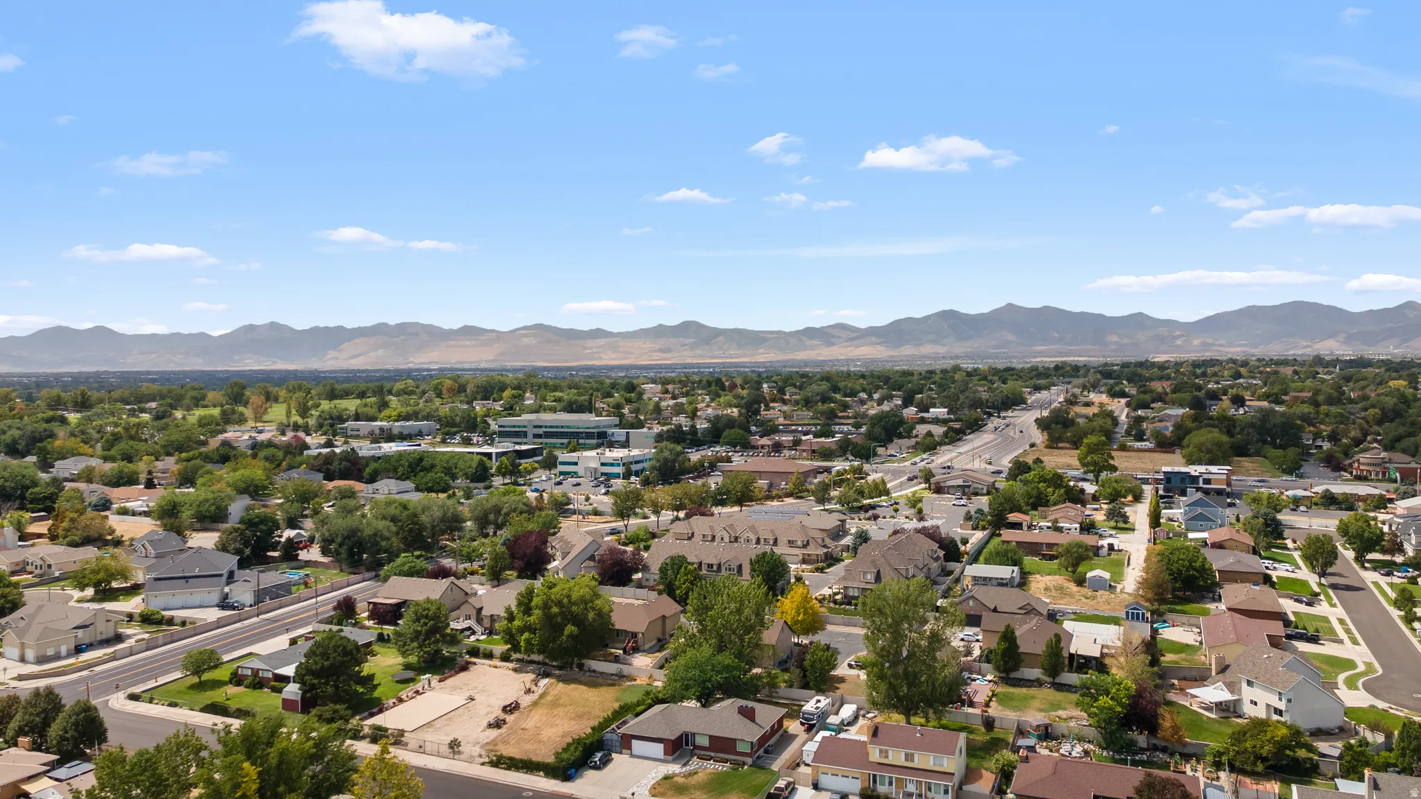 Sprawling community with mature trees, established residential areas, and mountain backdrop