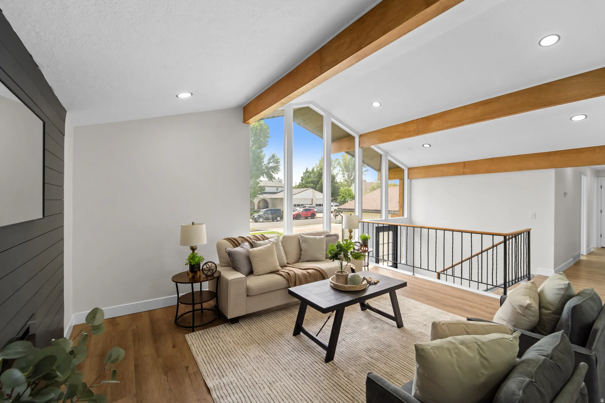 Vaulted ceiling with exposed wood beams, expansive window wall, wood-finish flooring, recessed lighting, and a dark shiplap accent wall