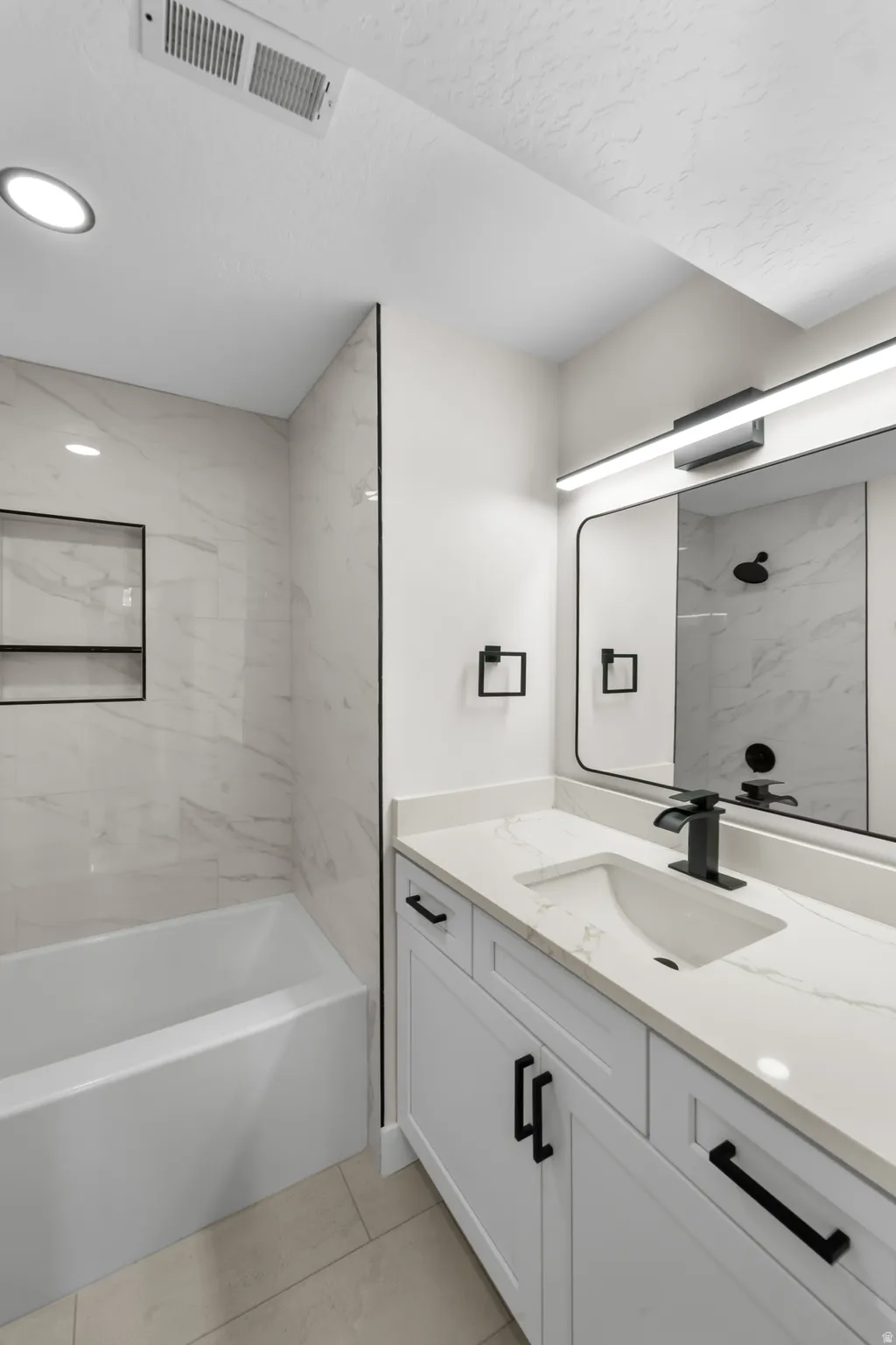 White vanity with matte black hardware, integrated sink, and a countertop