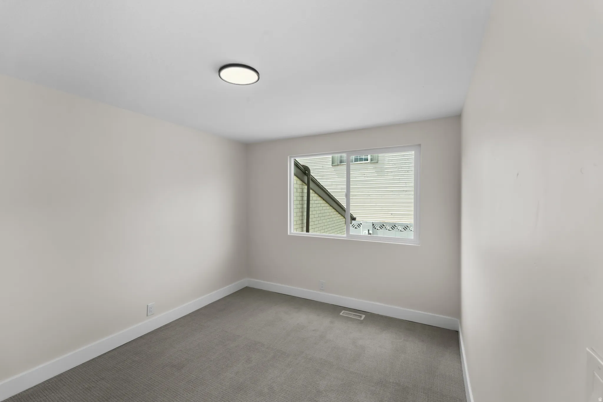Neutral wall tones, gray carpeting, and a flush-mount ceiling light