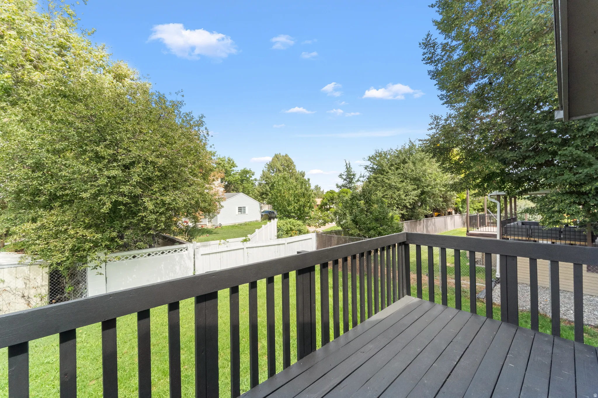 Exterior deck with dark wood-finish railing and decking overlooking a green lawn