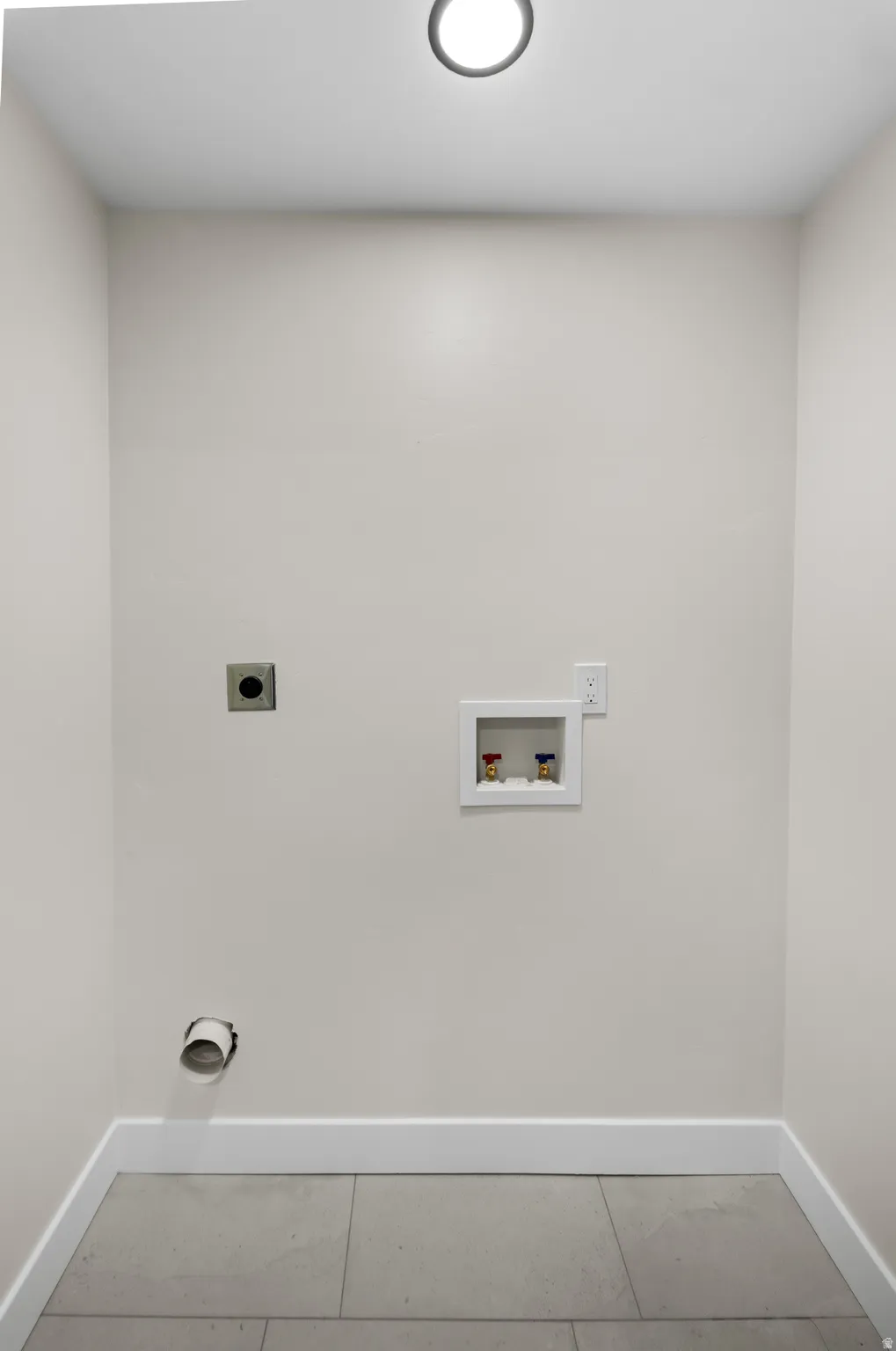 Recessed ceiling lighting, light gray wall paint, white trim, gray tile flooring, and laundry hookups