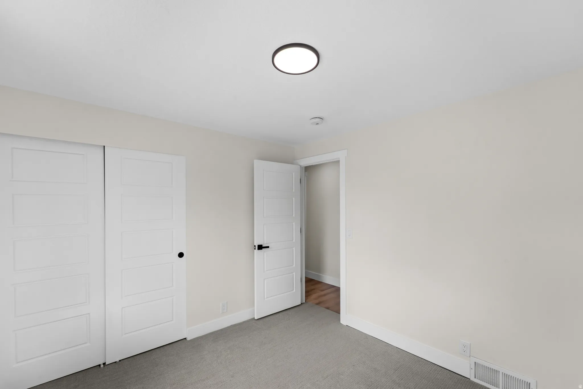 White interior doors with black hardware, recessed lighting, neutral wall color, and carpeted flooring