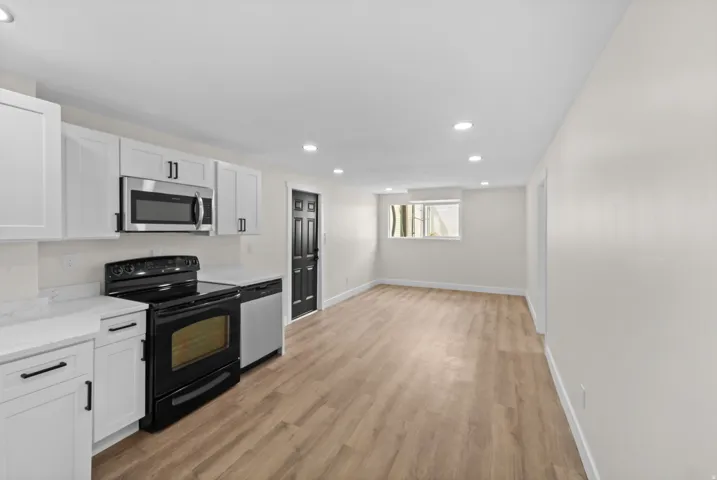 White cabinetry and countertops with a stainless steel microwave and black range