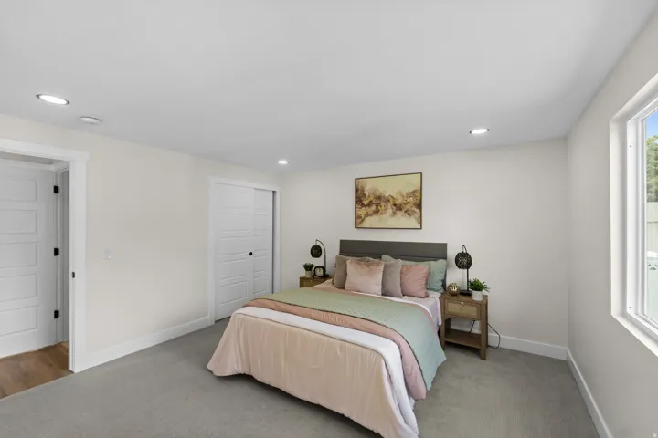 Recessed ceiling lighting, white trim, sliding closet doors, and a window with white casing