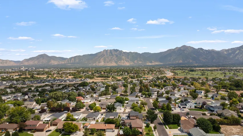 Expansive aerial perspective showcasing a residential neighborhood with surrounding mountains and a clear sky