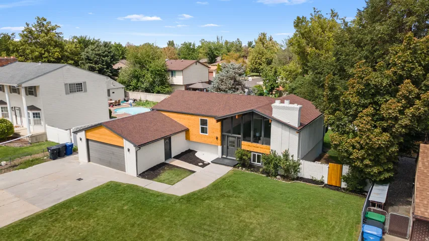Single-family residence featuring a two-car garage, pitched roof, and a mature tree canopy