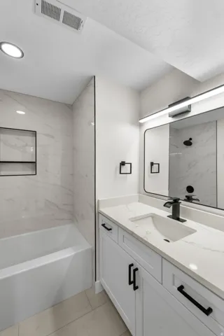 White vanity with matte black hardware, integrated sink, and a countertop