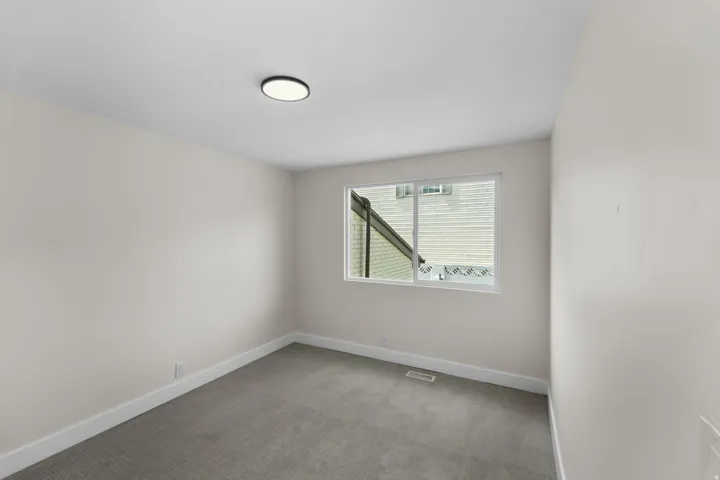 Neutral wall tones, gray carpeting, and a flush-mount ceiling light