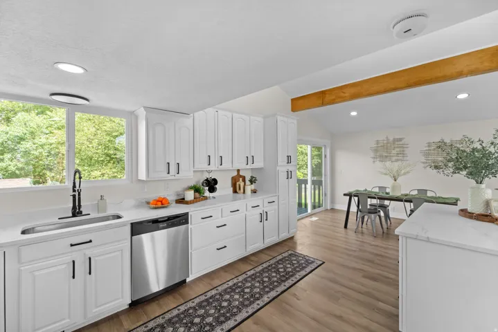 Kitchen with white cabinetry, stainless steel dishwasher, and wood-finish flooring