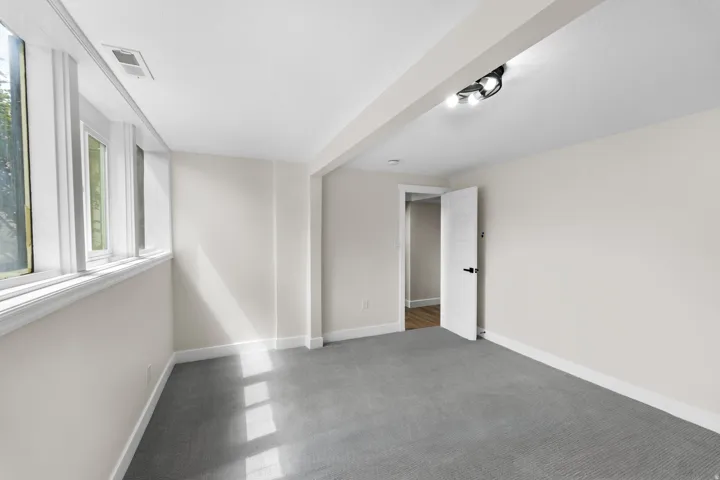 Wall-to-wall carpeting, white trim, recessed track lighting, and a paneled interior door with matte black hardware
