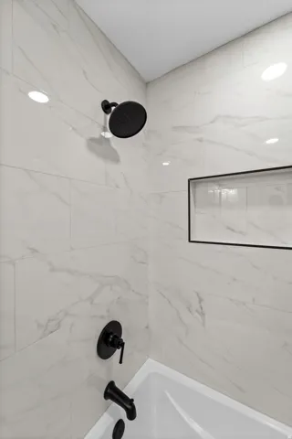 White tiled shower surround with dark contrasting fixtures