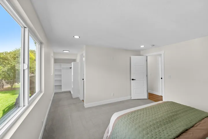 Recessed lighting, large windows, light gray carpeting, five-panel interior door, and built-in closet shelving
