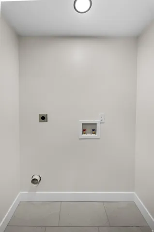 Recessed ceiling lighting, light gray wall paint, white trim, gray tile flooring, and laundry hookups