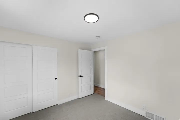 White interior doors with black hardware, recessed lighting, neutral wall color, and carpeted flooring