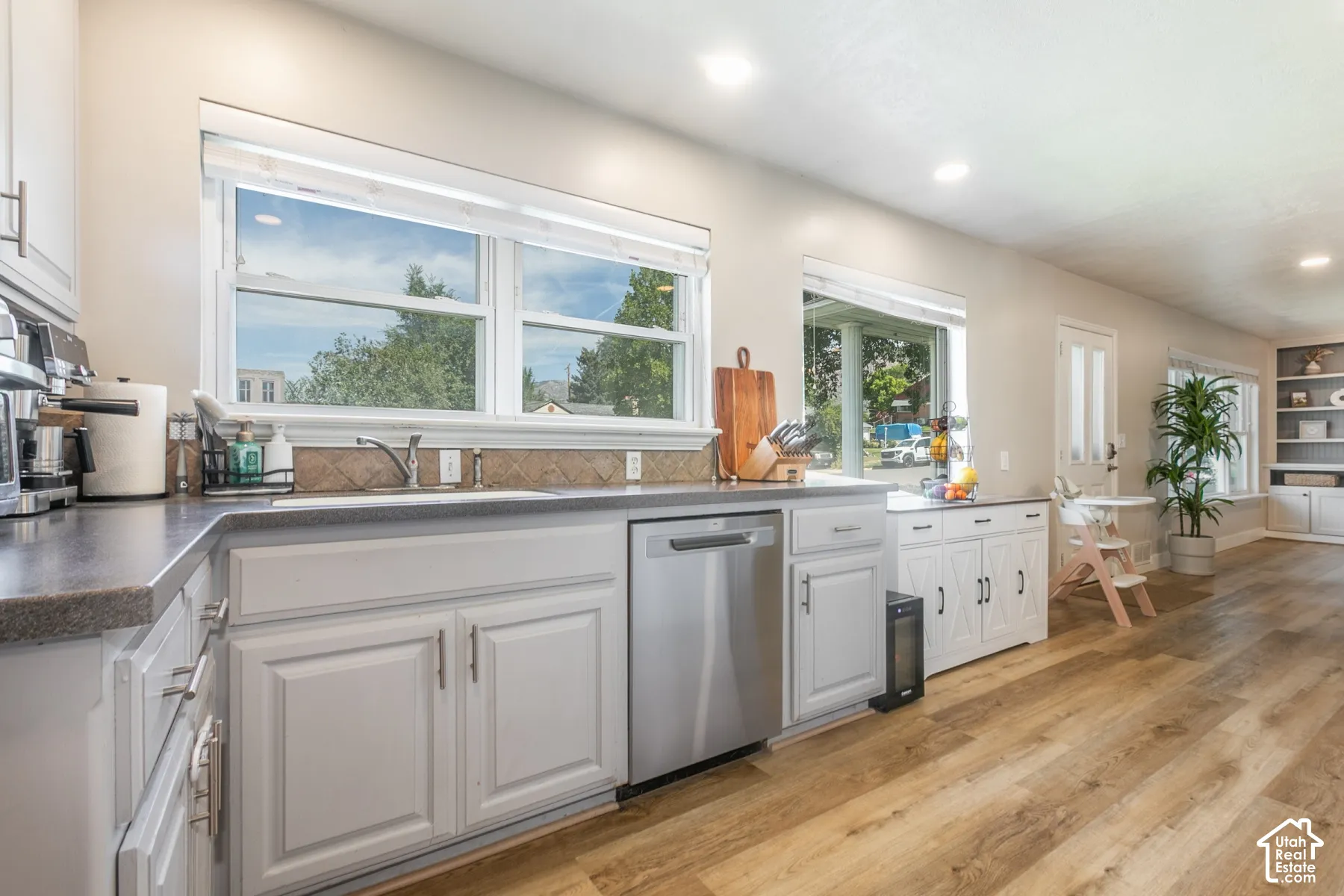 Kitchen featuring light wood-finish flooring, white cabinetry with silver-tone hardware, a stainless steel dishwasher, and recessed lighting