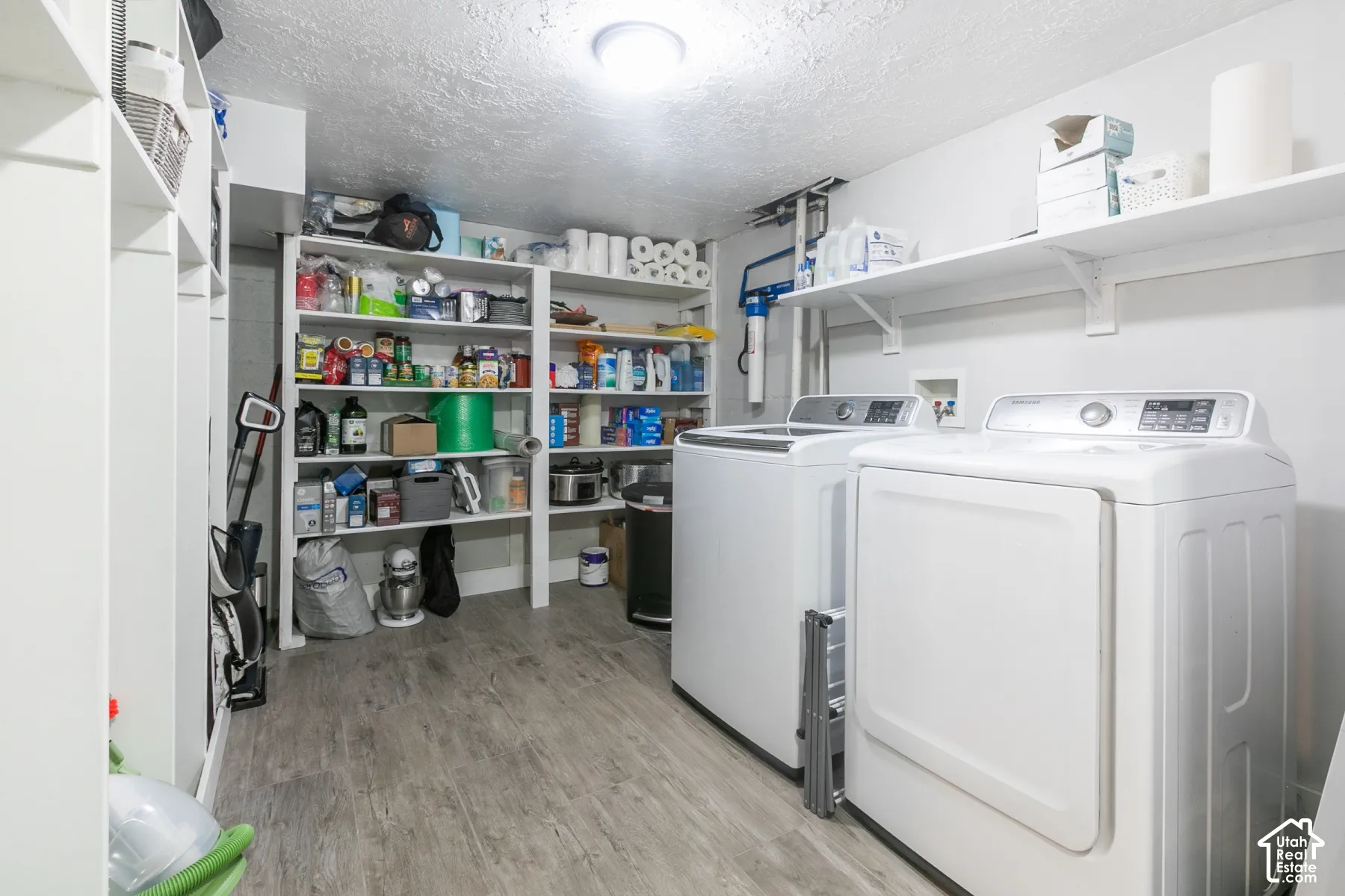 Utility area with wood-finish flooring, built-in shelving, and two appliances
