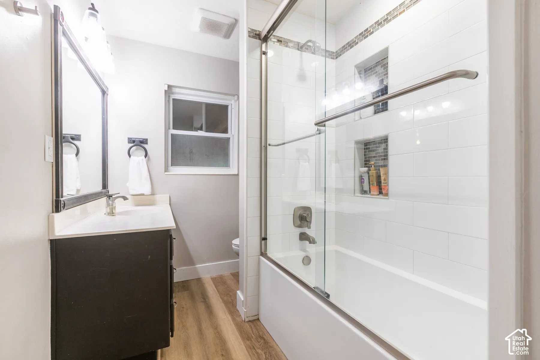 Wood-finish flooring with a vanity featuring a light-colored countertop