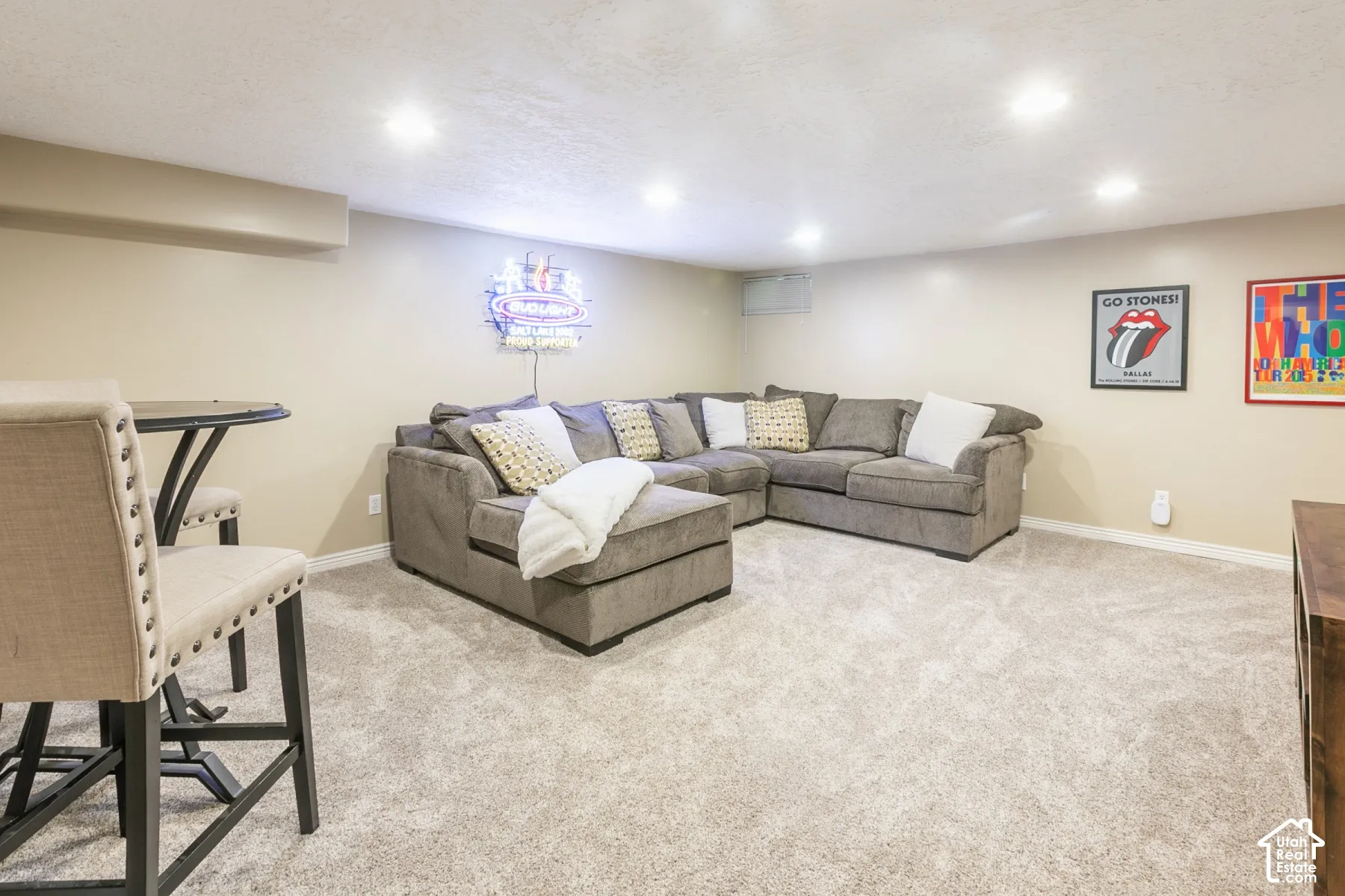 Recessed lighting illuminates the carpeted flooring and neutral wall tones