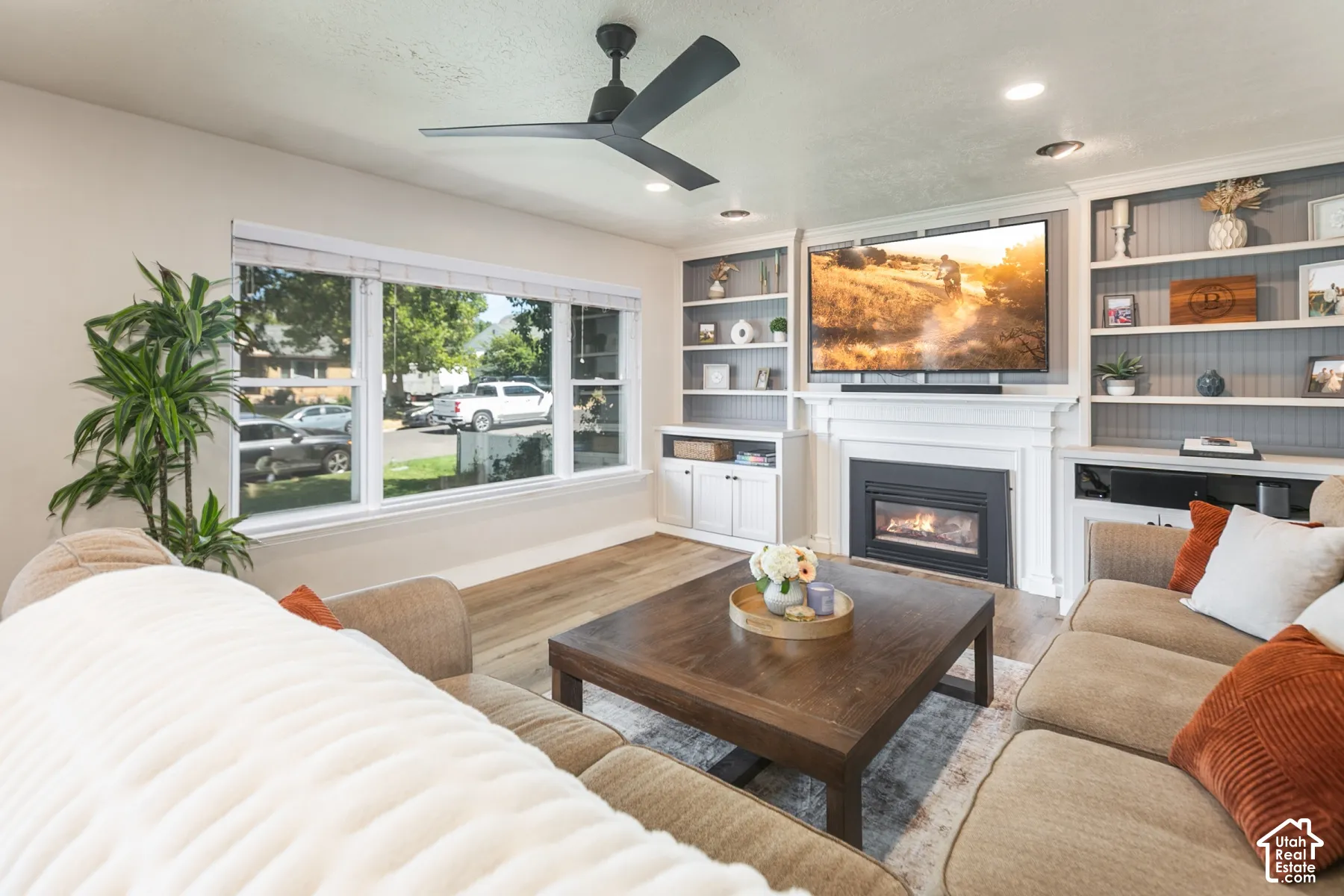 Built-in shelving, integrated fireplace, large picture windows, wood-finish flooring, and recessed lighting