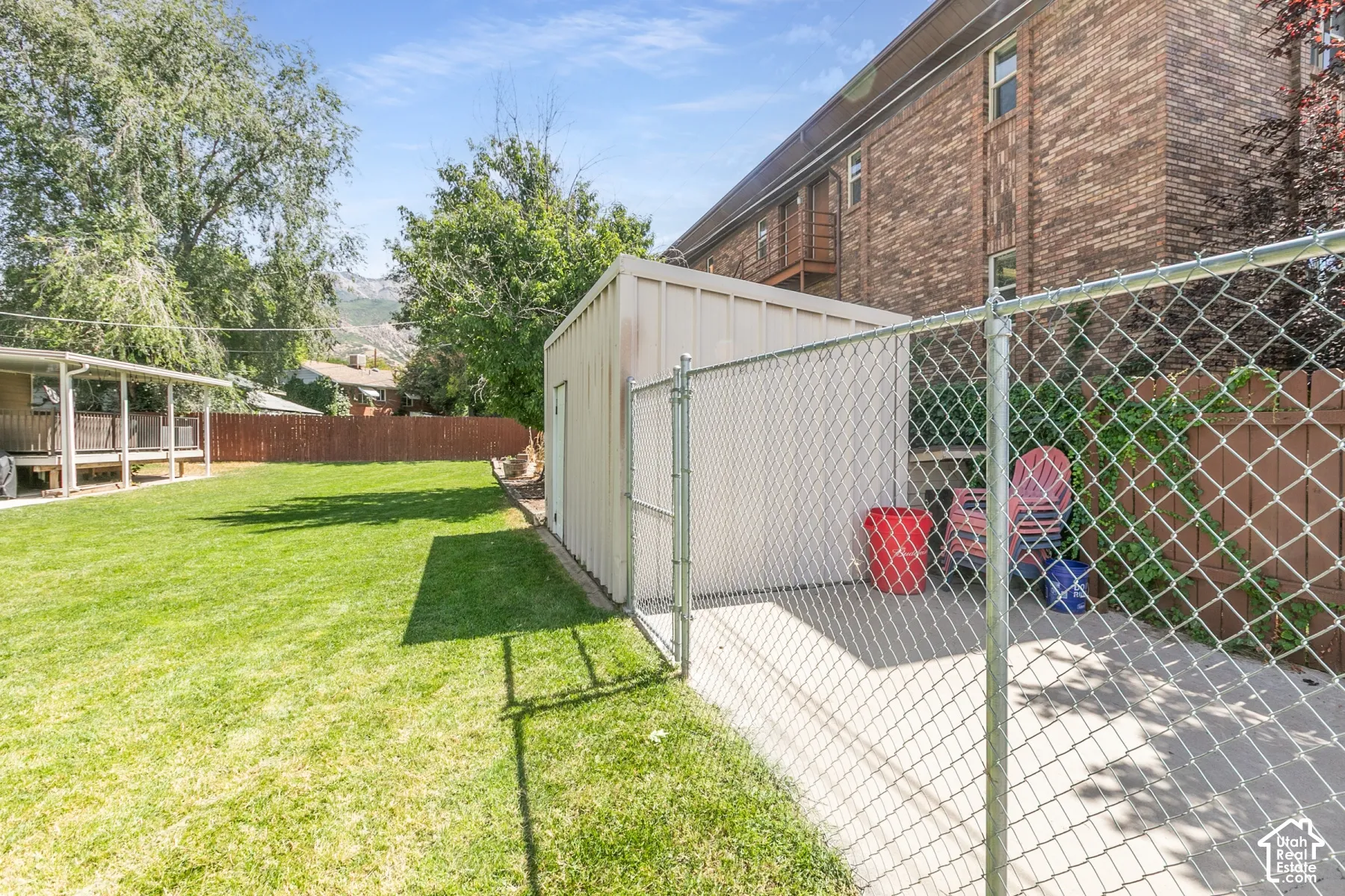 Expansive fenced yard featuring a storage shed, concrete pad, and covered patio with decking