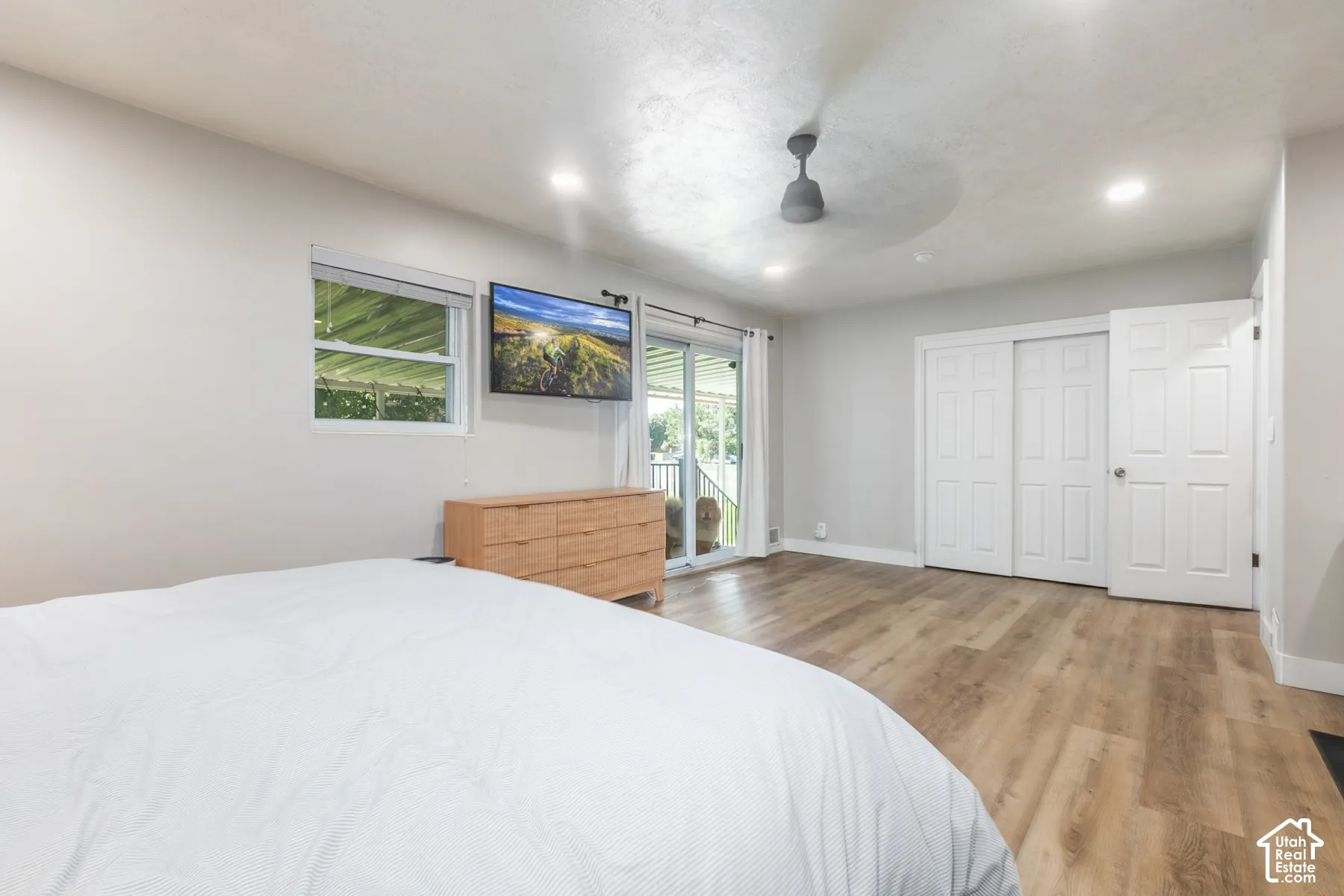 Recessed lighting, ceiling fan, wood-finish flooring, white sliding closet doors, and glass sliding doors to outdoor space