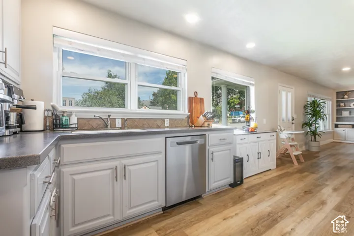 Kitchen featuring light wood-finish flooring, white cabinetry with silver-tone hardware, a stainless steel dishwasher, and recessed lighting
