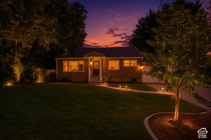 Siding exterior with a covered entry, established landscaping, walkway lighting, and a paved driveway