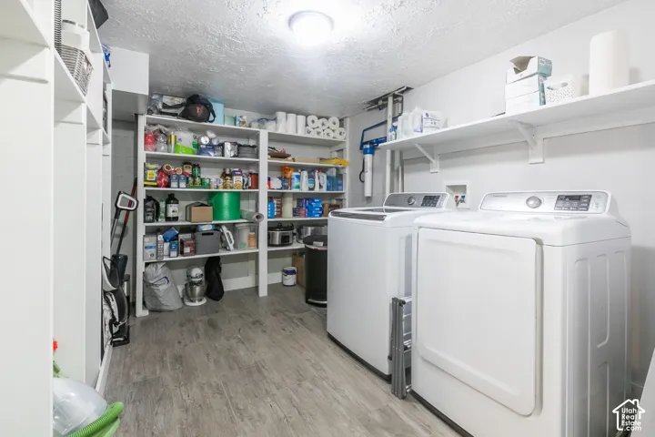 Utility area with wood-finish flooring, built-in shelving, and two appliances