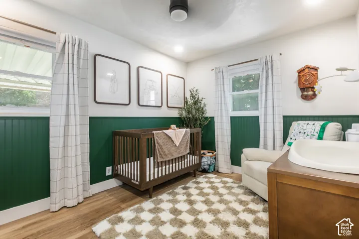 Recessed ceiling lighting, wood-finish flooring, two large windows, white walls, and green wainscoting