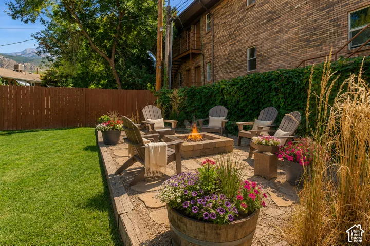 Patio area featuring flagstone paving, a built-in fire pit, and a retaining wall with raised garden beds