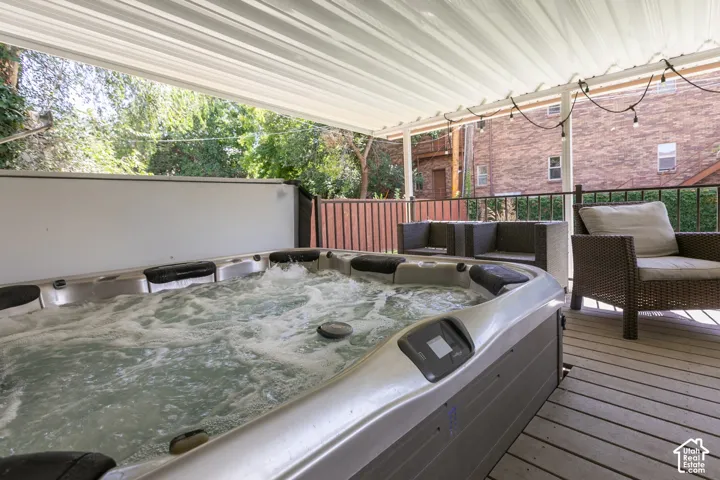 Deck featuring a hot tub, string lights, and a white overhead canopy