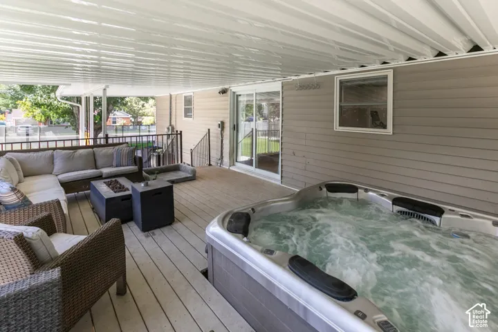 Covered outdoor deck with an integrated hot tub, privacy railing, and a sliding glass door entry point