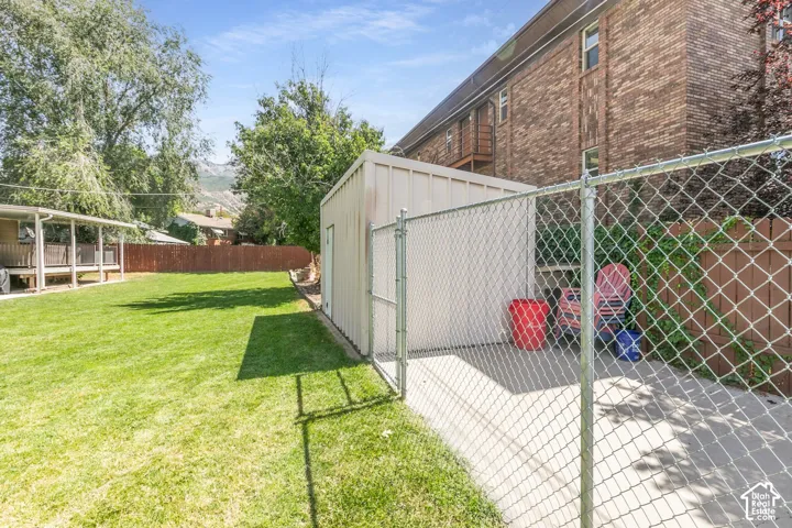 Expansive fenced yard featuring a storage shed, concrete pad, and covered patio with decking