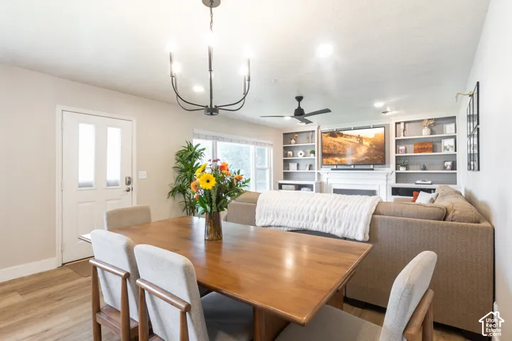 Open-concept living space with wood-finish flooring, a white paneled entry door with frosted glass inserts, and a black chandelier