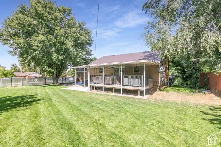 Expansive lawn with mature trees, screened-in porch, covered deck, and a fenced perimeter