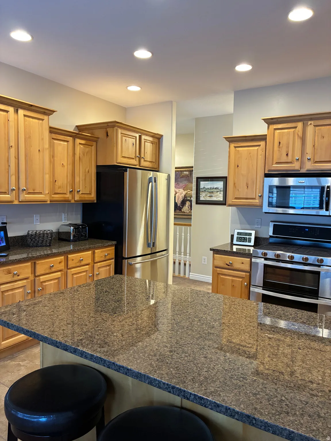 Kitchen featuring a large island with a substantial countertop, wood cabinetry, stainless steel appliances, and recessed lighting