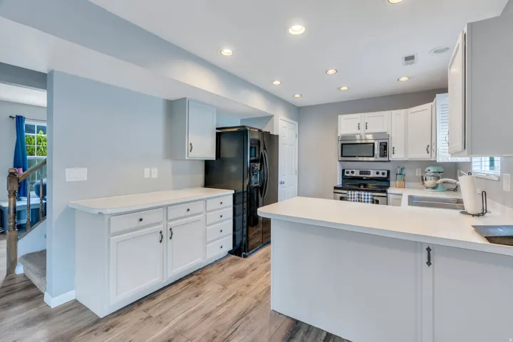 Kitchen featuring white cabinetry, light countertops, wood-finish flooring, recessed lighting, and stainless steel appliances